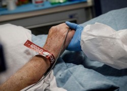 Một y tá nắm tay một bệnh nhân Covid 19 được điều trị trong phòng chăm sóc đặc biệt  (ANSA)