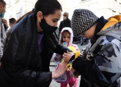 Giúp gắn dây màu Vàng Xanh vào tay trẻ Ucraina trong bước đón tiếp ban đầu  (ANSA)